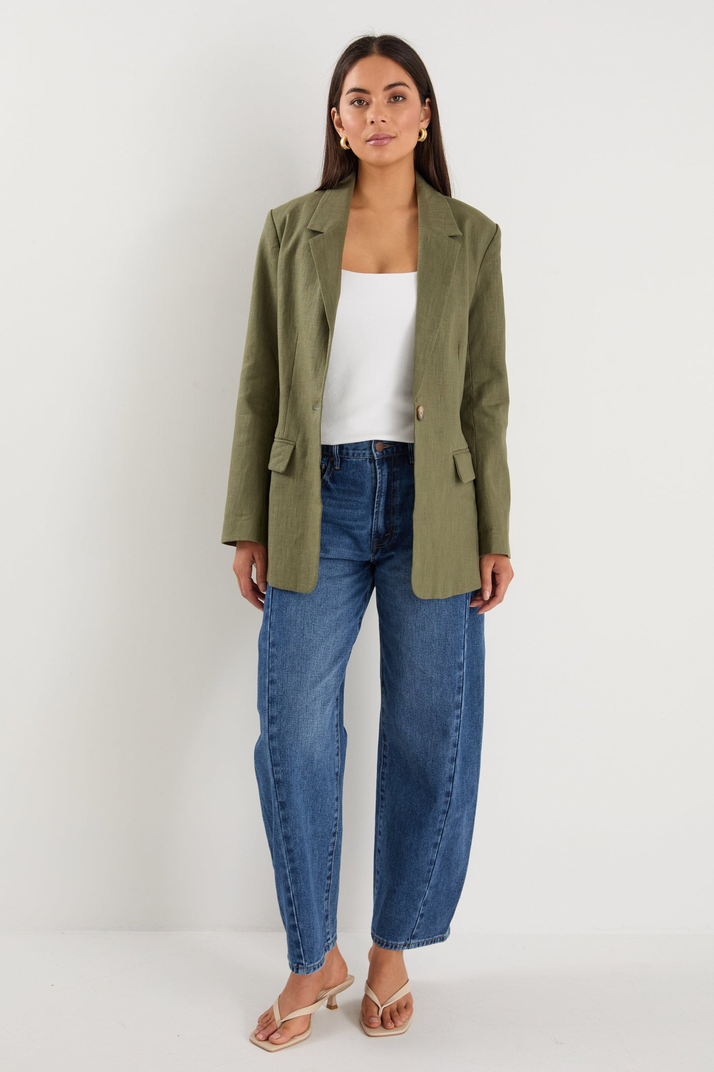 Model wears a green linen blazer with blue jeans
