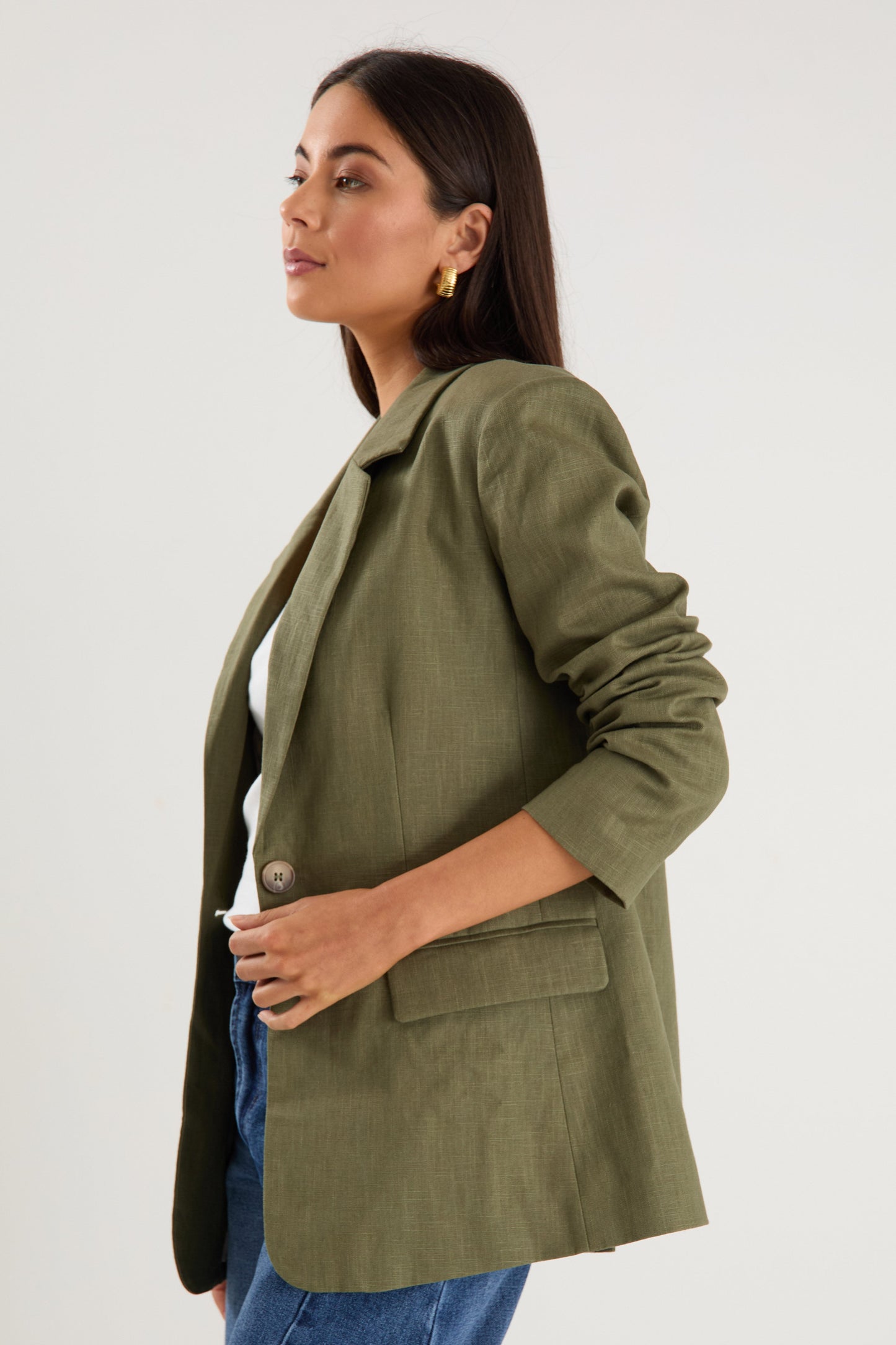 Model wears a green linen blazer with blue jeans