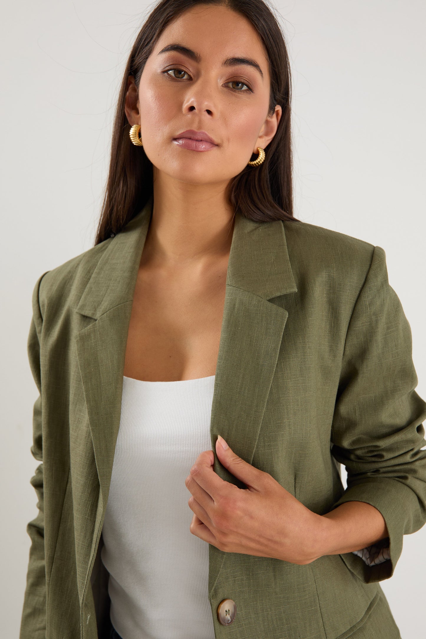 Model wears a green linen blazer with blue jeans