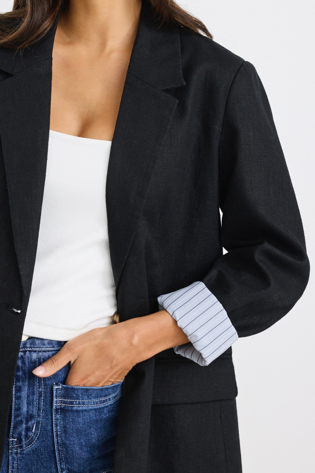 model wears a black linen blazer with blue stripe lining
